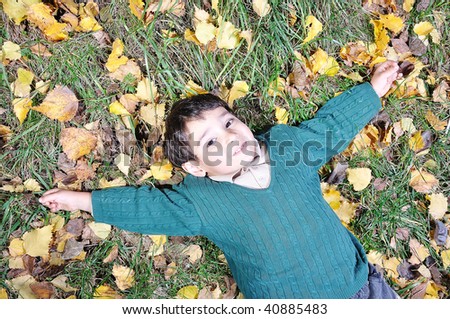 Little cute kid laying on the fall ground
