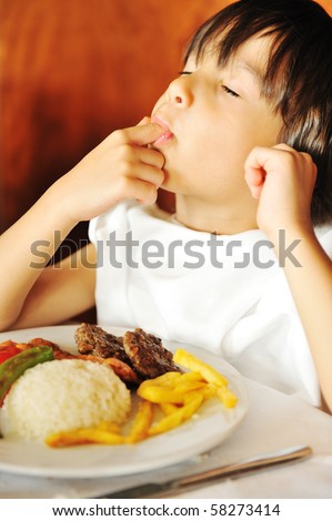 Real enjoying food, cute kid with finger in his mouth