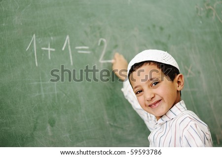 Very cute and positive kid smiling and writing on school board