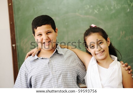 Two happy friends in front of green classroom board, school activities