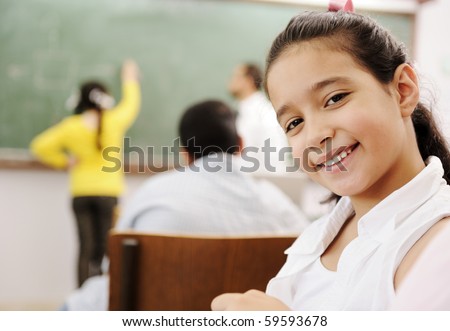 Adorable girl smiling in school classroom and behind her class activities Adorable girl smiling in school classroom and behind her class activities