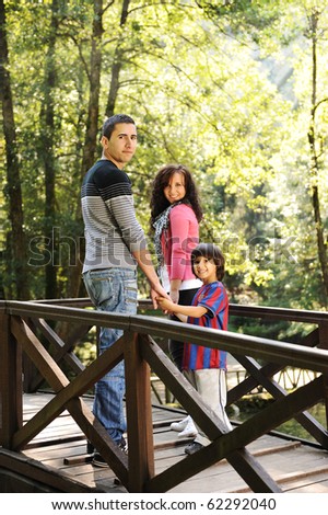 Beautiful scene of young happy family walking in nature together: mother, father and son