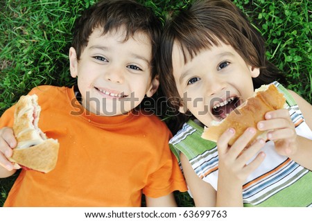 Two cute boys laying on ground in nature and happily eating healthy food