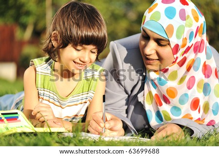 Mother and son learning together in nature, muslim - eastern cultural islamic clothes
