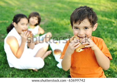 Small group of children in nature eating snacks together, sandwiches, bread