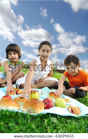 Small group of children eating together in nature, picnic, beautiful scene