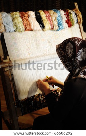 Woman working at the loom. Oriental Muslim national crafts. Focus on the fabric.