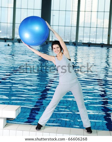 Woman at the gym with a pilates ball beside the pool