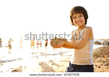 Kid on beach in sand playing, people around, summer hot nice time