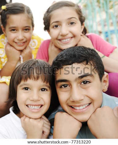 Vertical photo of children group, four friends smiling outdoor, boys and girls closeup