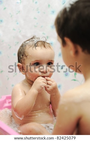 Adorable baby boy taking a bath with soap suds on hair