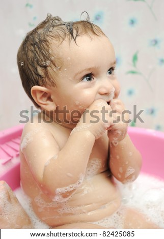 Adorable baby boy taking a bath with soap suds on hair