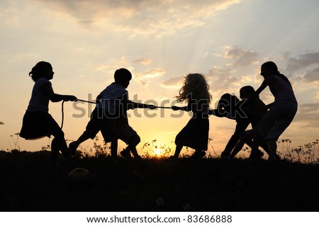 Silhouette, group of happy children playing on meadow, sunset, summertime