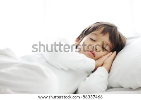 Kid on sleeping bed, happy bedtime in white bedroom