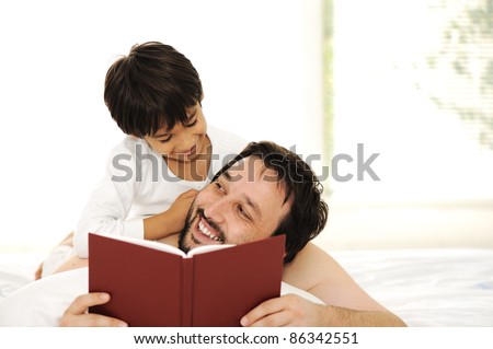 Father and son in bed, reading book together