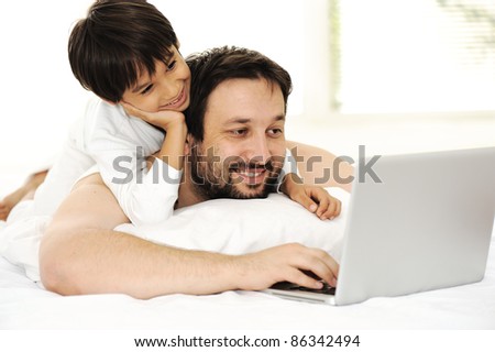 Father and son in bed, using laptop together, happy time