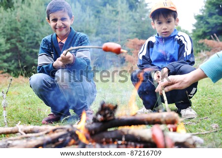 Barbecue in nature, group of people preparing sausages on fire (note: shallow dof)
