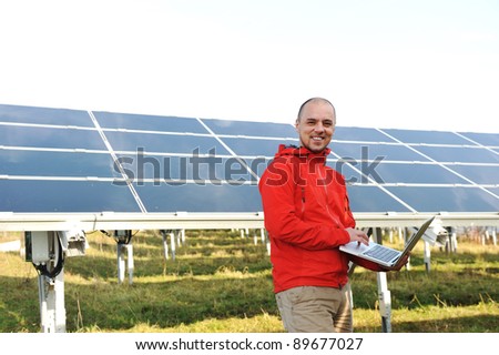 Engineer using laptop, solar panels in background