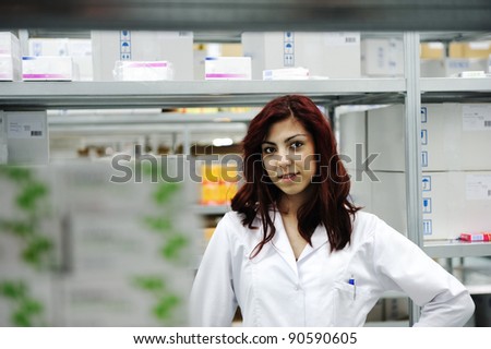 Young cheerful female worker in modern drug warehouse