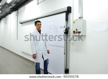 Young worker opening  door of industrial refrigerator