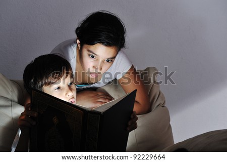 Brother and sister reading light book at night