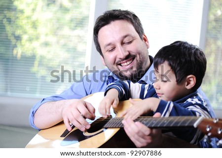 Father and son playing guitar at home