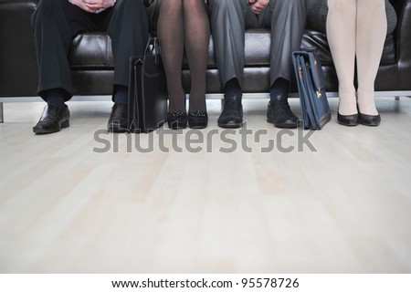 Business people legs sitting on couch at office