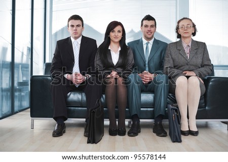 Four business people sitting in a row on sofa