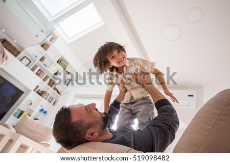 Cheerful young boy having fun with father on sofa