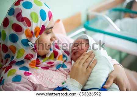 Arabic Muslim mother carrying her child in hospital bed immediately after delivery