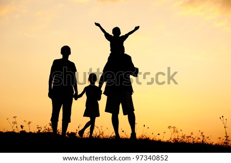 Happy family on meadow at summer sunset