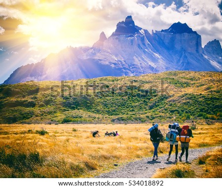 Group of travelers with backpacks walk along a trail towards a mountain ridge.Backpackers style. Concept of active leisure