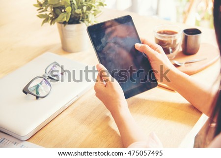 Beautiful business working woman using Ipad while working with laptop and reading report , graphs , charts, document at work. Business woman working at her desk.