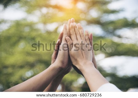 Teamwork Concept. Group of people make a high five in the air to show power of team building. Multiethnic working together in group seminar. Team collaboration in business situation