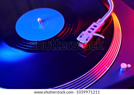 Turntable vinyl record player. Sound technology for DJ to mix & play music. Vintage vinyl record player on a background decorations for a party, bright disco lights. Needle on a vinyl record