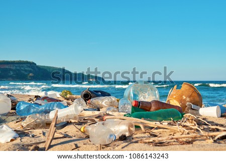 Spilled garbage on the beach of the big city. Empty used dirty plastic bottles. Dirty sea sandy shore the Black Sea. Environmental pollution. Ecological problem. Moving waves in the background