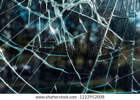 Criminal incident at the bus stop. Shooting a pistol. Hole and cracks in the glass of a city bus stop. Cracked glass texture against the blue sky. Cracked glass with a hole from a bullet. Vandalism
