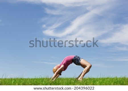 Young girl doing a back arch in a meadow