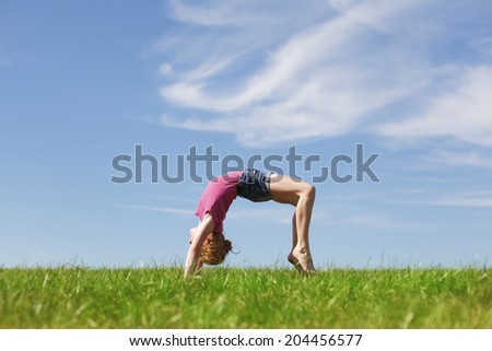 Young girl doing a back arch in a meadow