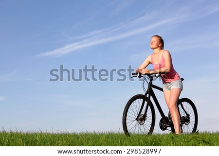 Beautiful young girl enjoys a ride on a bike outside