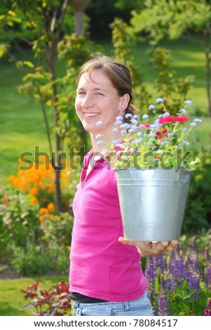 A young gardening woman enjoys a sunny day in the garden