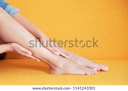Young asian girl suffering from pain in leg at home