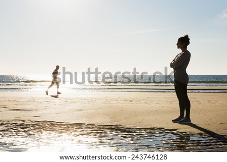 Young woman coach waiting her pupil at sunset on the beach.