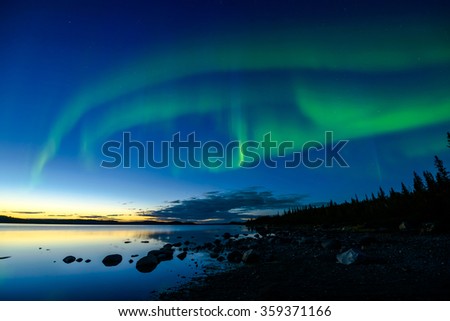 Northern Lights After Sunset - Bands of Northern Lights appear above a rocky lake right after the sun sets.