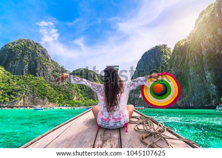 Traveler woman in summer dress joy relaxing on wooden boat, Maya beach, Phi Phi island, near Phuket, Krabi, Travel Thailand, Beautiful destination place Asia, Summer holiday outdoor vacation trip