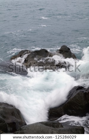 Sea waves hitting the rocks, in the cold sea
