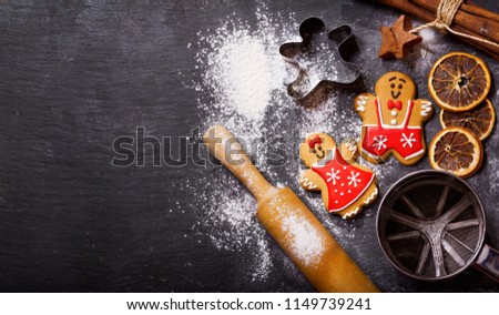 Christmas food. Homemade gingerbread cookies with ingredients for christmas baking and kitchen utensils on dark table, top view