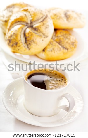 cup of coffee with baked rolls with poppy