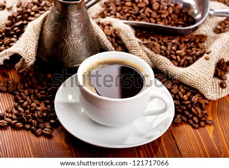 cup of black coffee and beans on wooden table