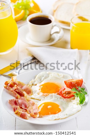 breakfast with fried eggs, toasts, juice, coffee and fruits